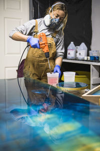 Female resin artist mixing with respirator mask