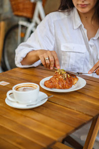 Midsection of woman having food on table