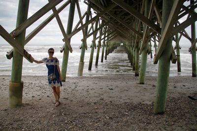 Portrait of woman standing under pier at beach