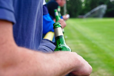 Midsection of man holding beer bottle