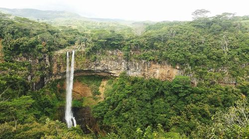 Scenic view of waterfall in forest against sky