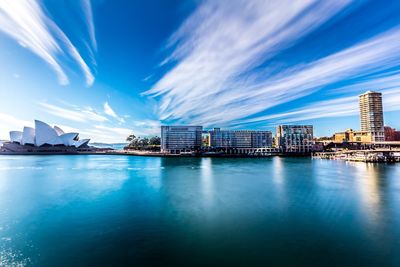 City at waterfront against cloudy sky