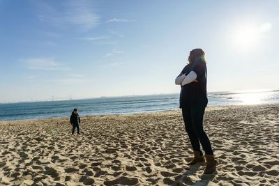 Rear view of couple standing on beach against sky