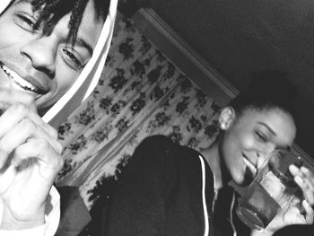 Portrait of young man holding camera at home