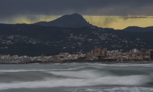 Scenic view of sea by townscape against sky