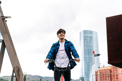 Young man standing against sky in city