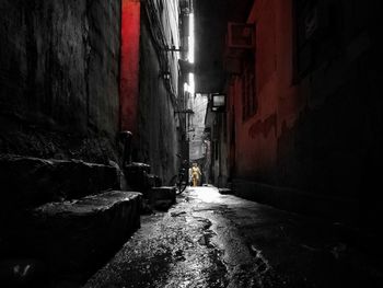 Narrow alley amidst buildings in city at night