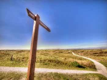 Low angle view of windmill on field against blue sky