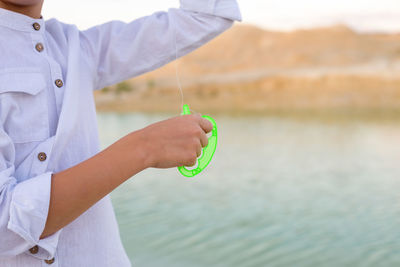 A child's hand holds a fishing line from a kite.