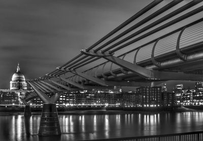 Illuminated bridge over river against sky in city at night