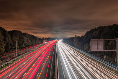 Light trails on road against sky at night