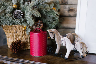 A souvenir horse, a raspberry tin can against a background of fir branches in a wicker basket