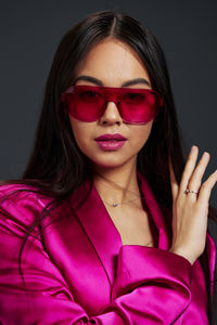 Portrait of young woman wearing sunglasses against black background