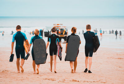 Rear view of people at beach against sky