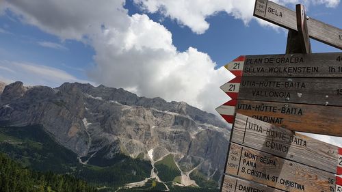 Road sign by mountain against sky