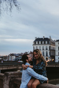 Couple kissing against sky in city