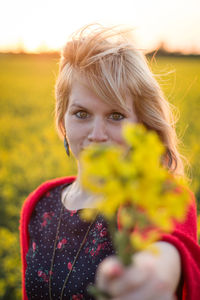 Close-up portrait of young woman with flowers in field