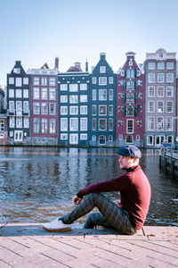 Man sitting by river in city