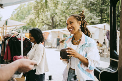 Smiling female customer holding container while shopping at flea market