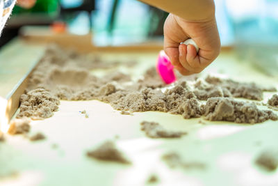 Cropped hand of child playing with sand