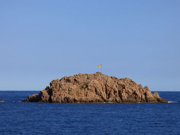 Rock formation in sea against clear sky