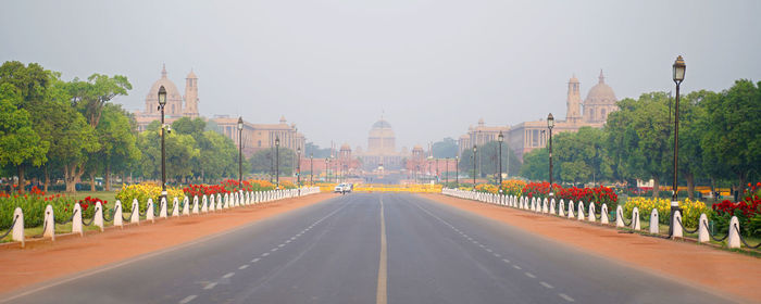 Road passing through city against sky