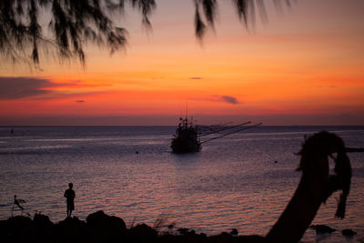 Silhouette people on beach against sky during sunset