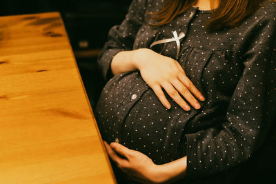 Midsection of pregnant woman sitting on table