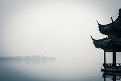 Cropped image of traditional gazebos on lake during foggy weather