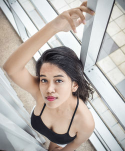 Portrait of beautiful young woman standing against railing