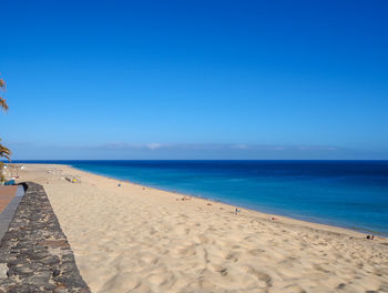 Scenic view of beach against clear blue sky