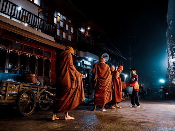 People standing on illuminated street at night