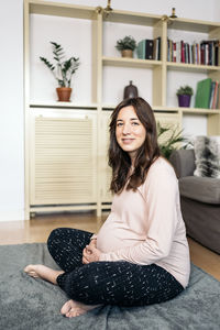 Portrait of smiling woman sitting on sofa at home