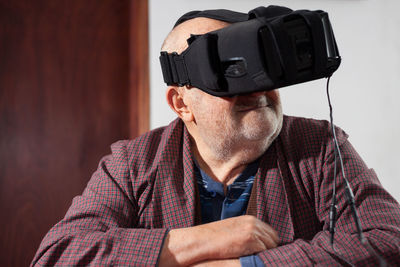 Senior man with virtual reality simulator at home