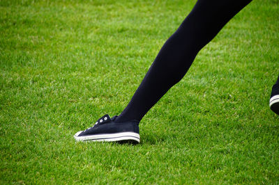 Low section of woman running on grassy field