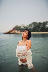 Sensuous young woman wearing bikini standing in sea