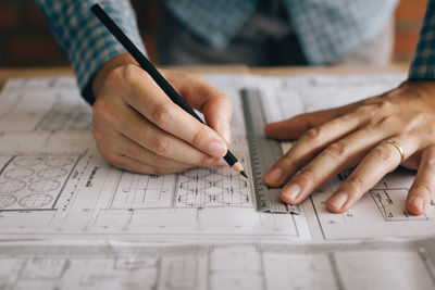 Cropped image of male architect drawing blueprint at desk