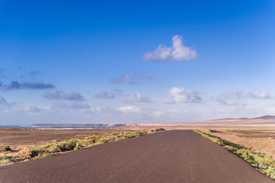 Road by landscape against blue sky