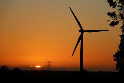 Silhouette windmill on field against sky during sunset