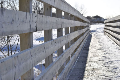 Snow covered footbridge over river against sky