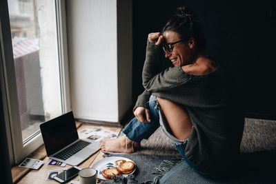 Smiling woman sitting by window at home