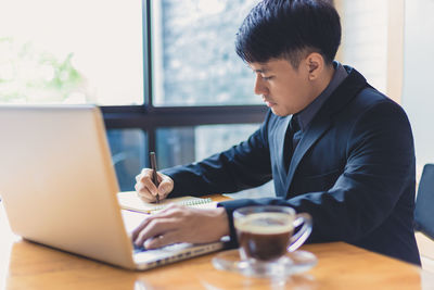 Man using mobile phone while sitting on table