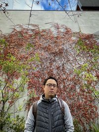 Portrait of young man looking away while standing against plants