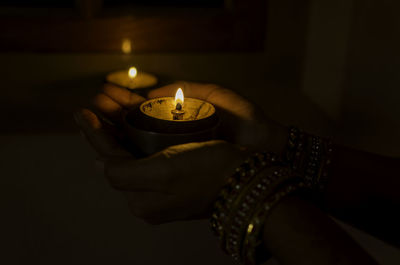 Close-up of hand holding lit candle