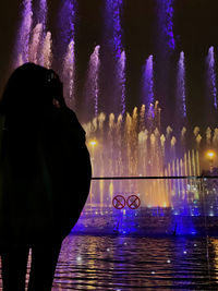 Digital composite image of silhouette man against illuminated lights in city at night