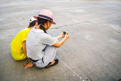 High angle view of siblings photographing with mobile phone on footpath