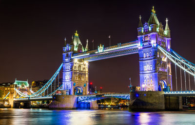 Illuminated bridge over river at night