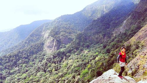 Young woman standing on mountain against sky