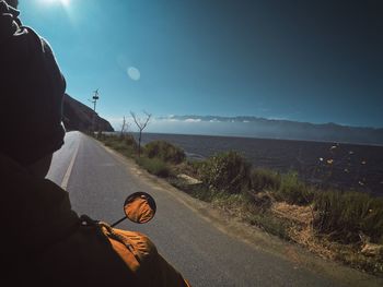 Rear view of man riding motorcycle on road against sky