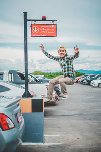 Full length portrait of happy man on car against sky